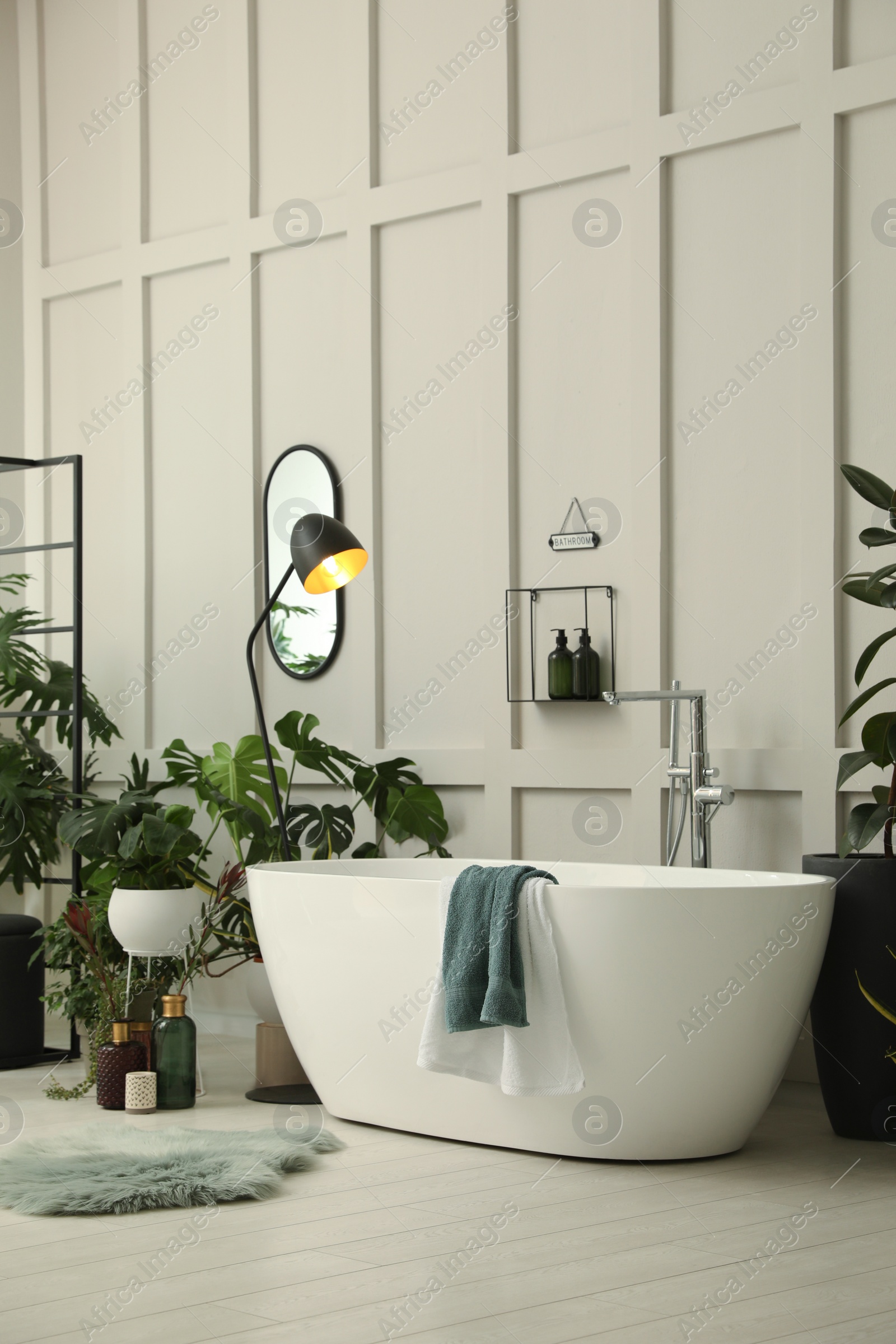 Photo of Stylish bathroom interior with modern tub and beautiful houseplants. Home design