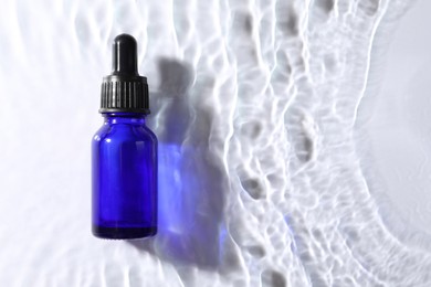Photo of Bottleface serum in water on white background, top view. Space for text