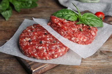 Photo of Raw meat cutlets for burger on wooden table, closeup