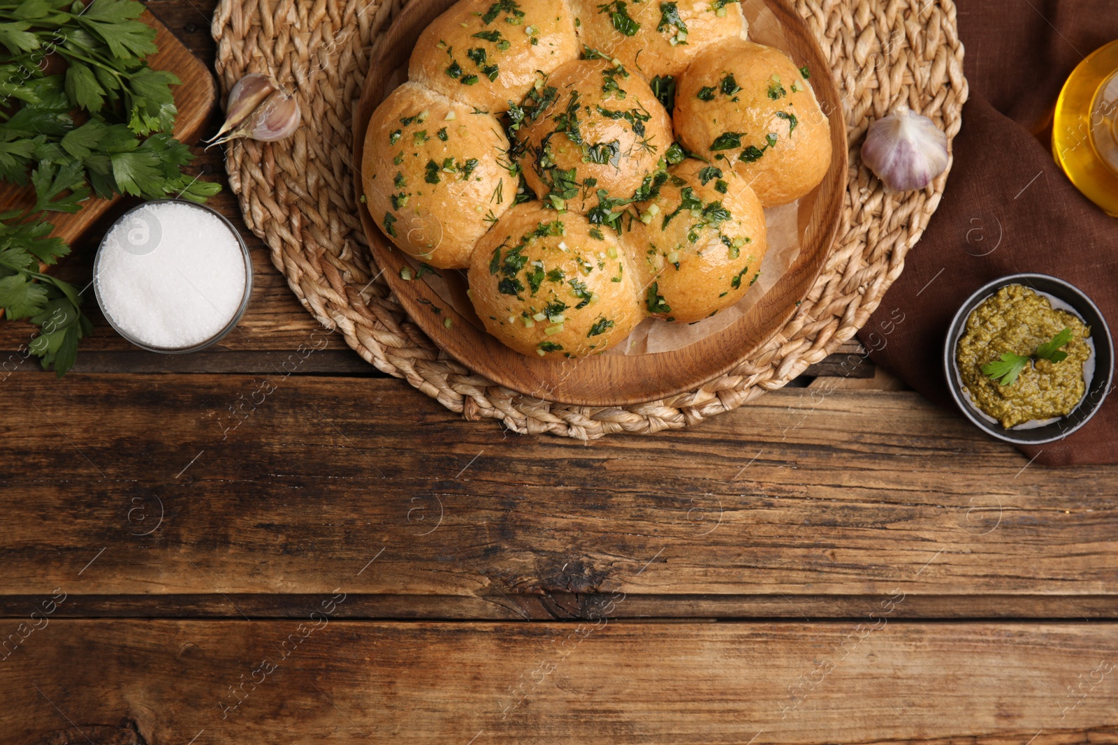 Photo of Traditional pampushka buns with garlic and herbs on wooden table, flat lay. Space for text