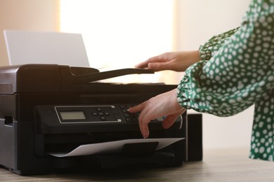 Photo of Woman using modern printer in office, closeup