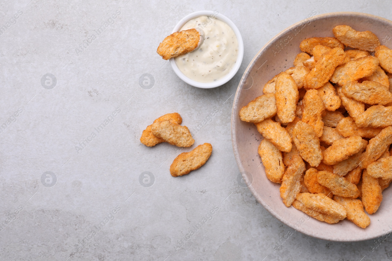 Photo of Crispy rusks and dip sauce on light table, flat lay. Space for text