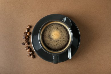 Cup of tasty coffee and beans on brown background, flat lay