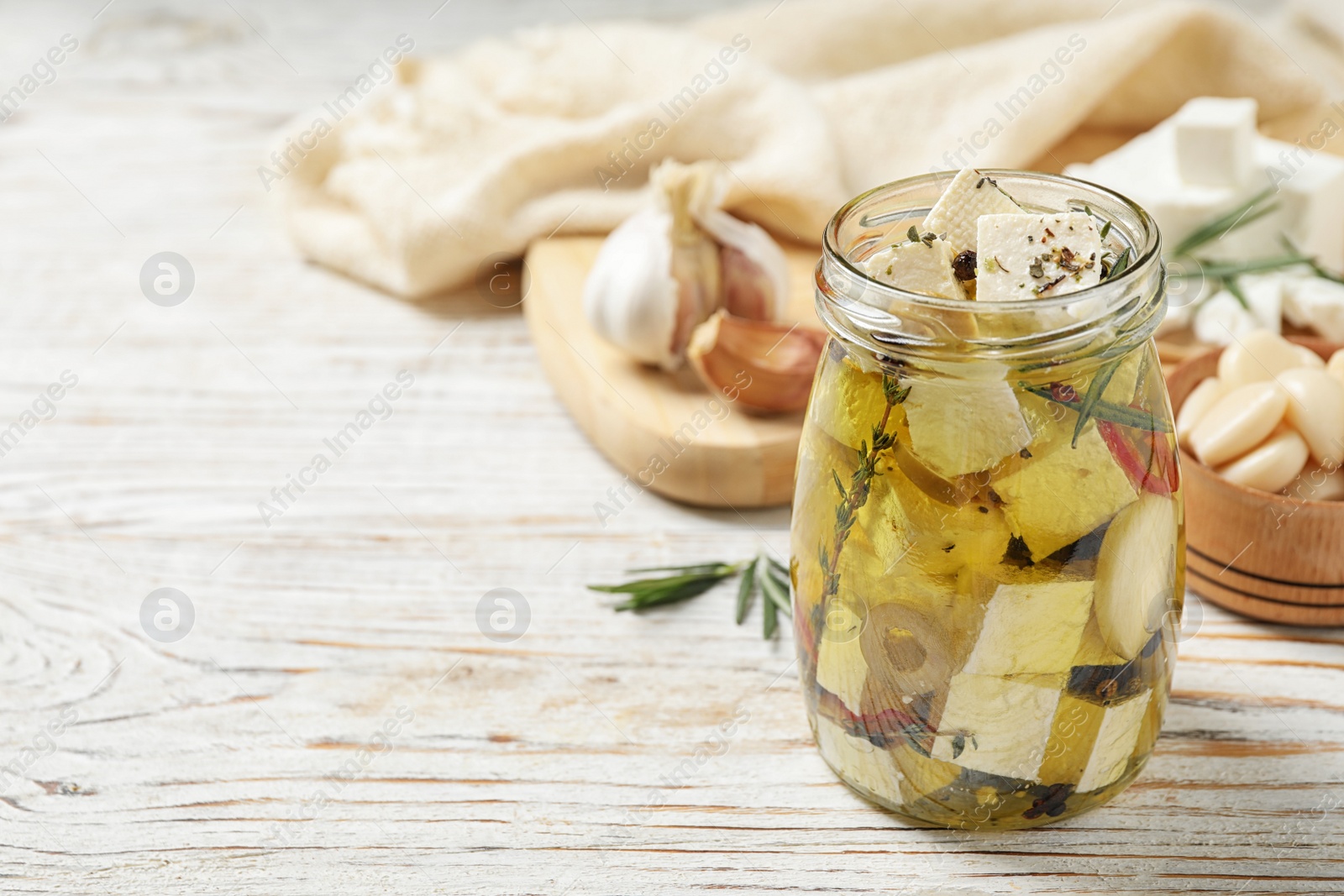 Photo of Composition with pickled feta cheese in jar on white wooden table, space for text