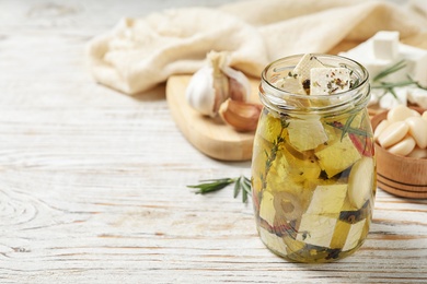 Photo of Composition with pickled feta cheese in jar on white wooden table, space for text