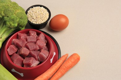 Raw meat in bowl and healthy products for pet on beige background. Space for text