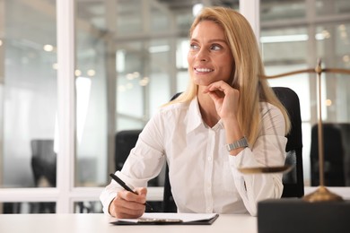 Smiling lawyer working at table in office, space for text