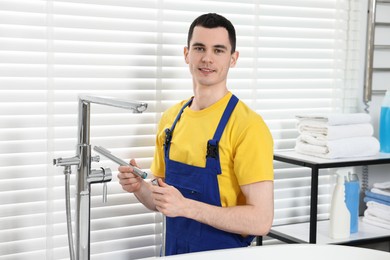 Photo of Portrait of smiling plumber repairing faucet in bathroom