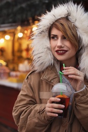 Woman with cup of mulled wine at winter fair