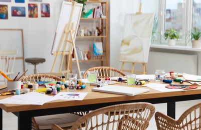 Photo of Artist's studio with different painting supplies on table. Creative hobby