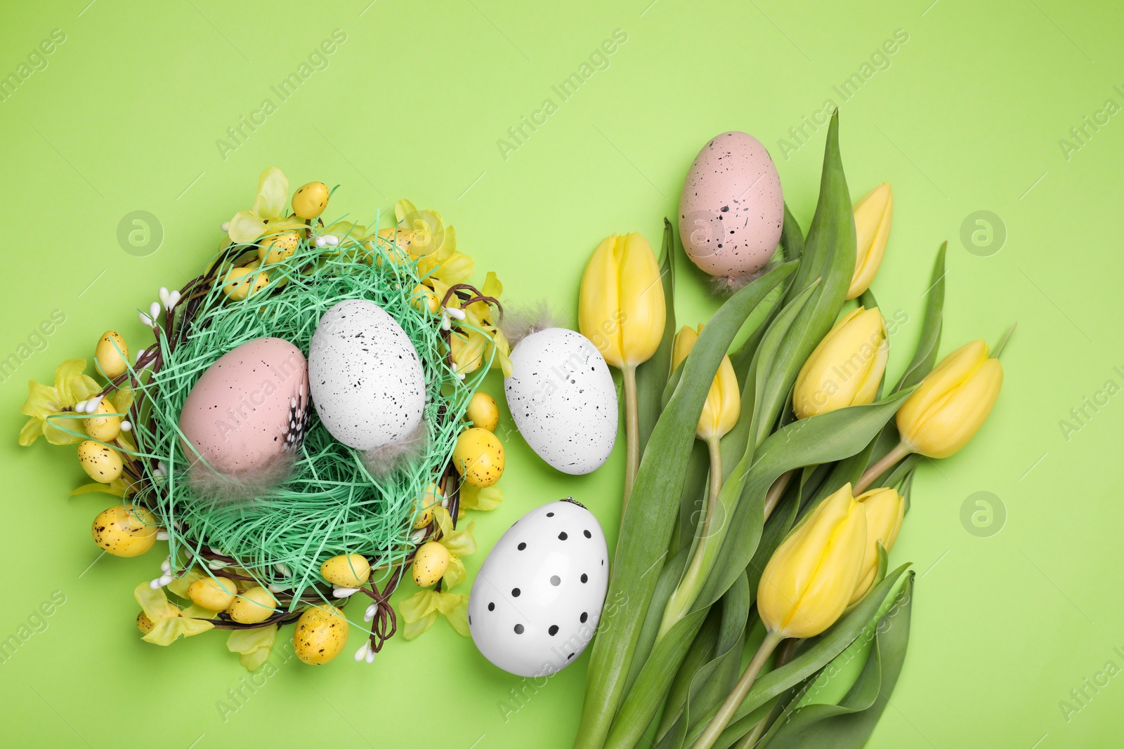 Photo of Flat lay composition with beautiful flowers and eggs on light green background. Easter celebration