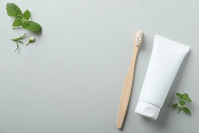 Flat lay composition with toothbrush, toothpaste and herbs on light grey background. Space for text