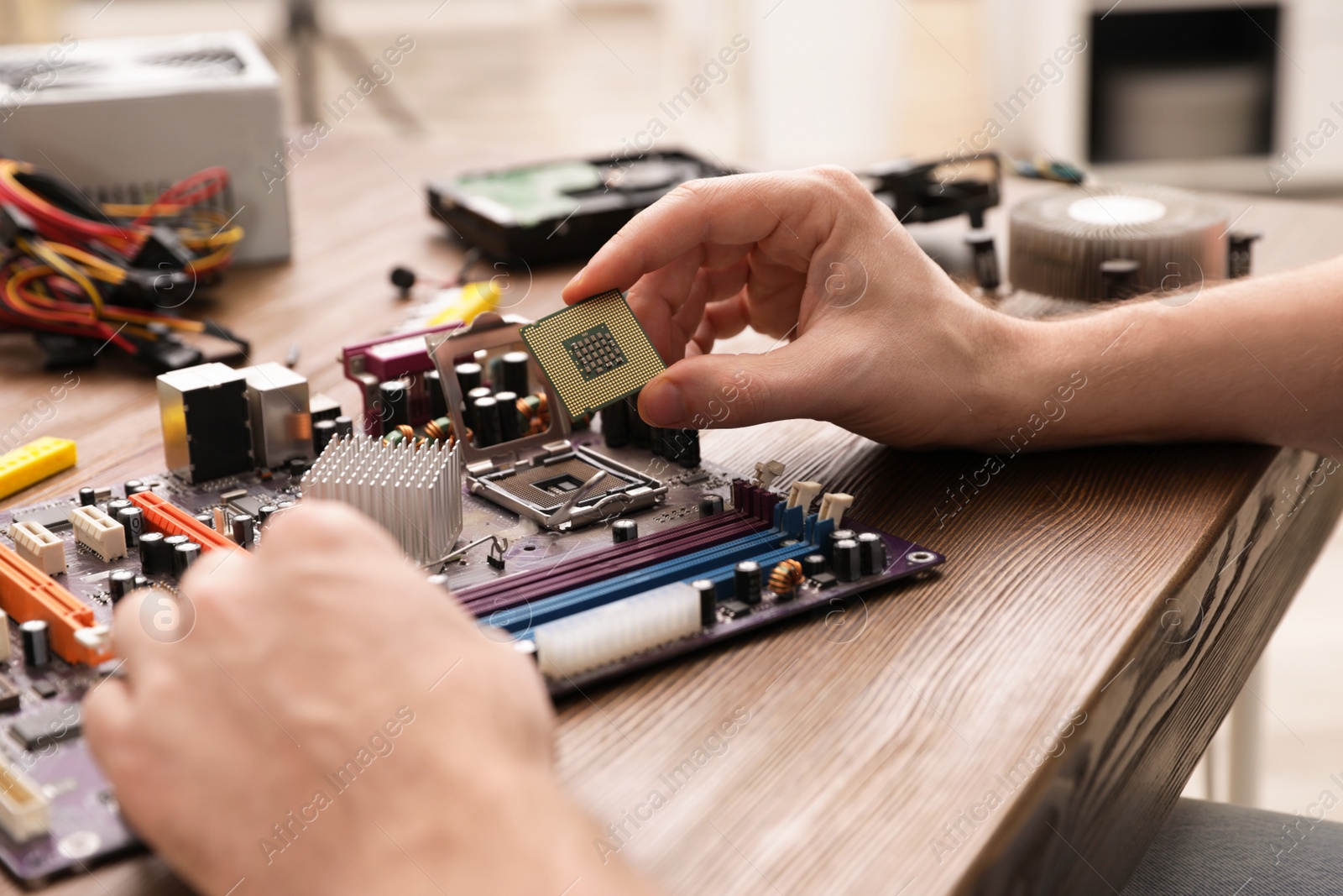 Photo of Male technician repairing motherboard at table, closeup