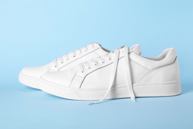 Photo of Pair of stylish white sneakers on light blue background