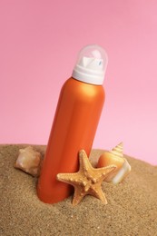 Photo of Sand with sunscreen, stone, starfish and seashell against pink background. Sun protection care