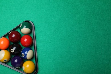Plastic rack with billiard balls on green table, top view. Space for text