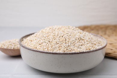 Raw barley groats in bowl on light table, closeup
