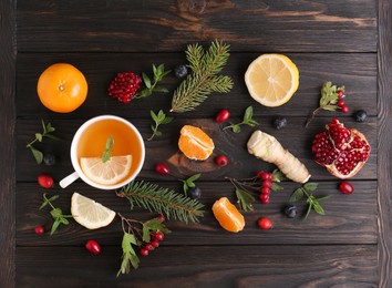 Flat lay composition with cup of delicious immunity boosting tea and ingredients on wooden table