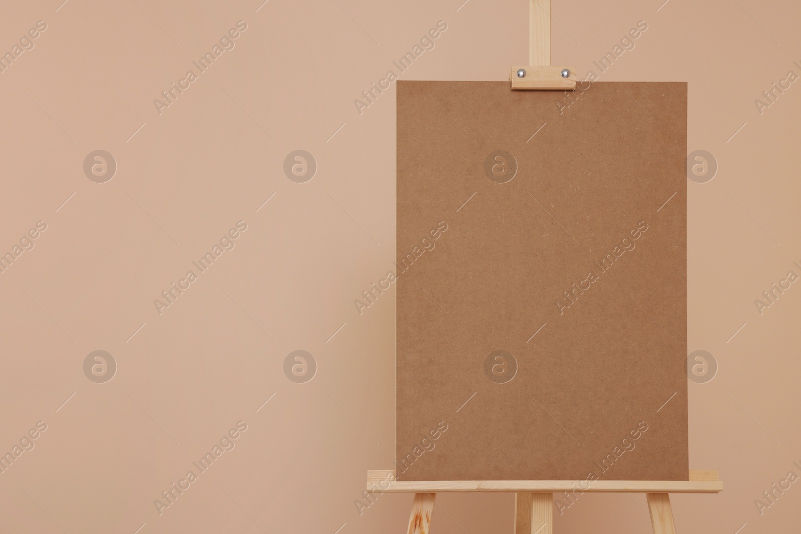 Photo of Wooden easel with blank board on beige background. Space for text