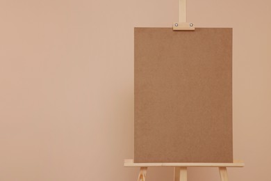 Photo of Wooden easel with blank board on beige background. Space for text