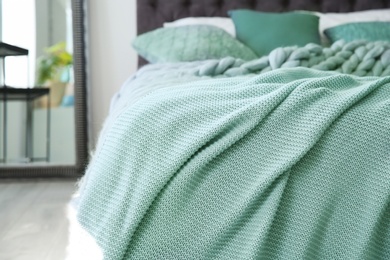 Photo of Warm knitted mint blanket on bed, closeup