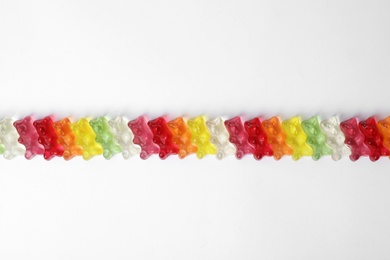 Row of delicious jelly bears on white background, top view