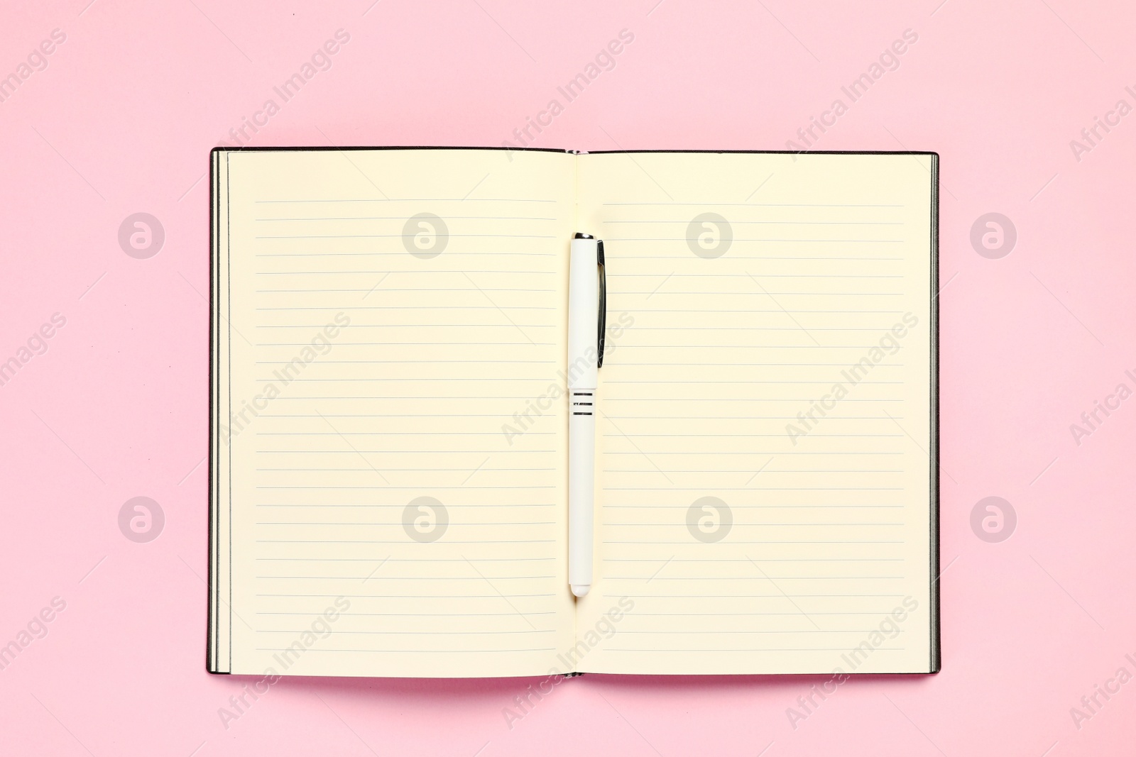 Photo of Top view of open planner with pen on colorful background