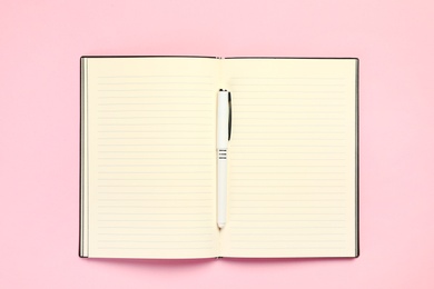 Photo of Top view of open planner with pen on colorful background