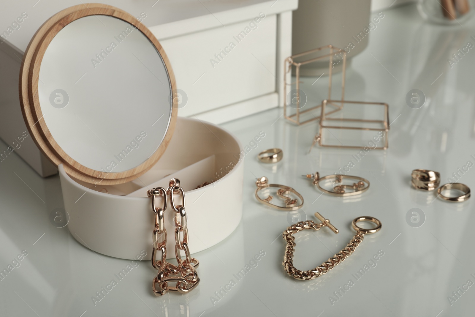 Photo of Jewelry box with mirror and stylish golden bijouterie on white dressing table