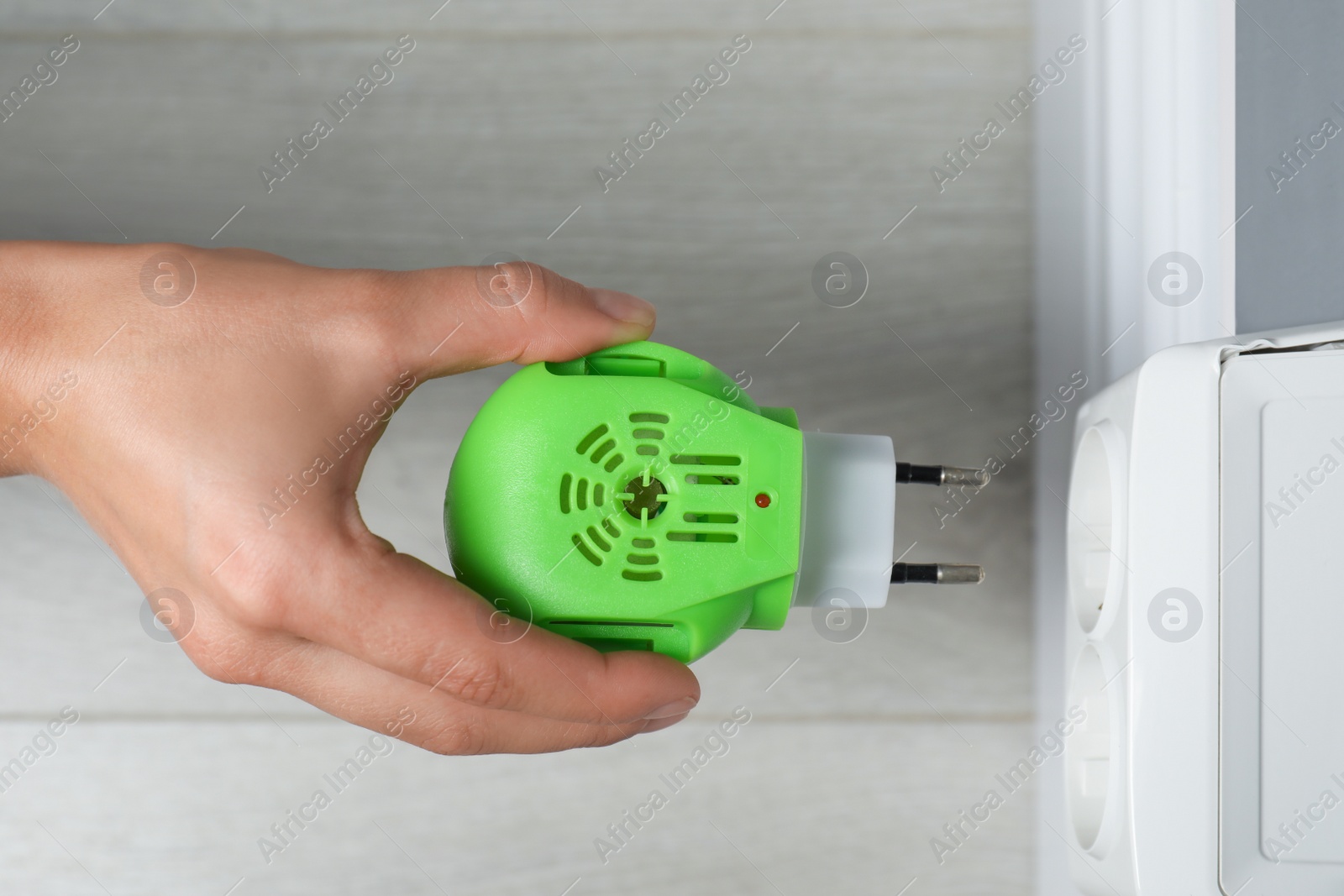 Photo of Woman plugging electric mosquito repellent at home, top view