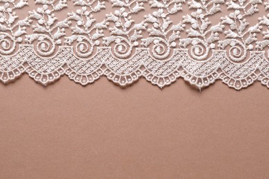 Photo of White lace on beige background, top view. Space for text