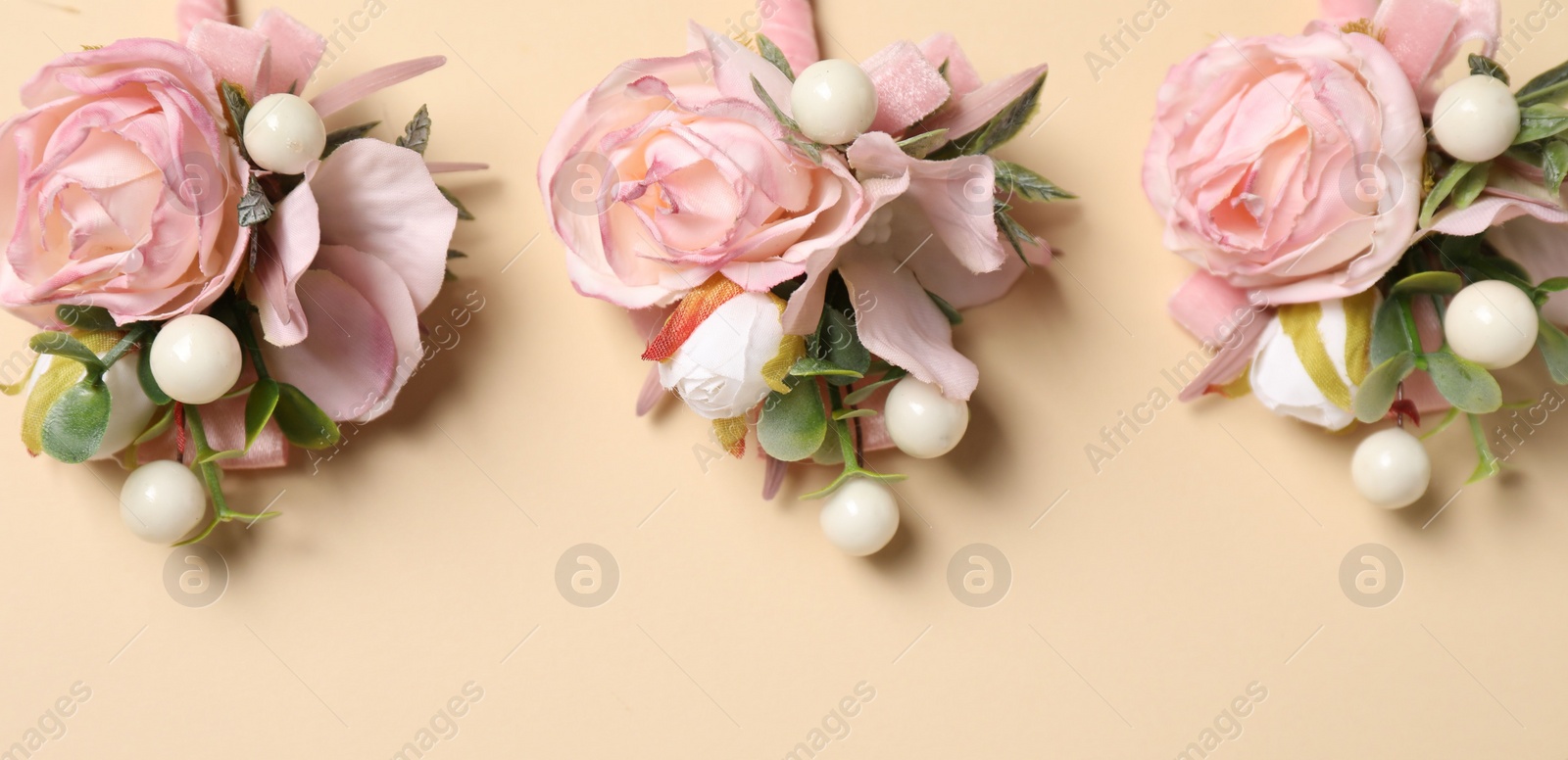 Photo of Stylish pink boutonnieres on beige background, flat lay