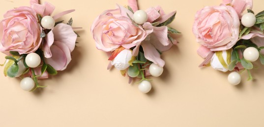 Photo of Stylish pink boutonnieres on beige background, flat lay