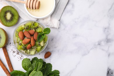 Delicious dessert with kiwi, almonds and mint on white table, flat lay. Space for text
