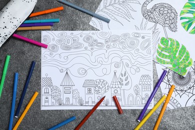 Photo of Antistress coloring pages and felt tip pens on grey table, flat lay