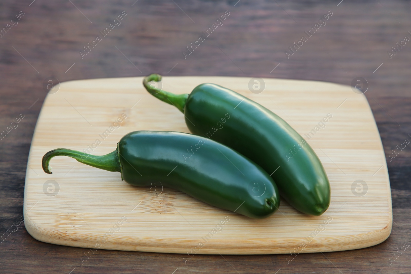 Photo of Fresh green jalapeno peppers on wooden table, closeup