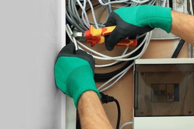 Photo of Electrician cutting wires in fuse box, closeup