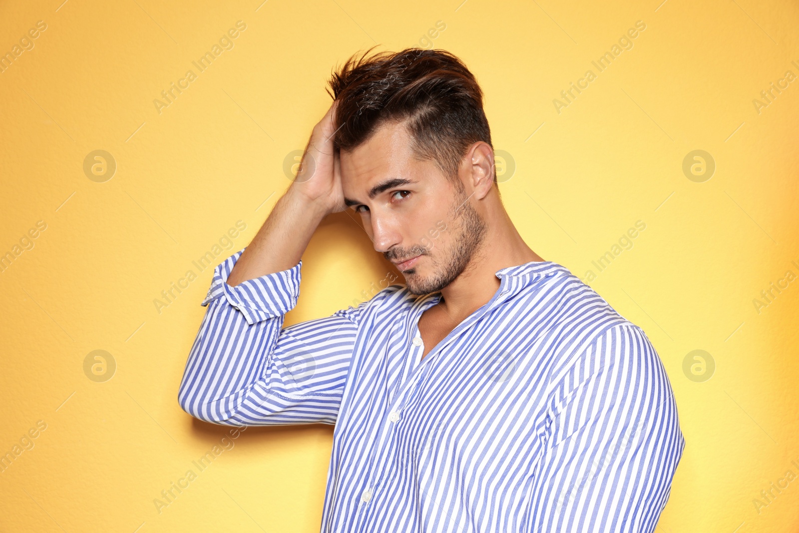 Photo of Young man with trendy hairstyle posing on color background