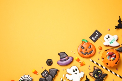 Flat lay composition with decorated gingerbread cookies on yellow background, space for text. Halloween celebration