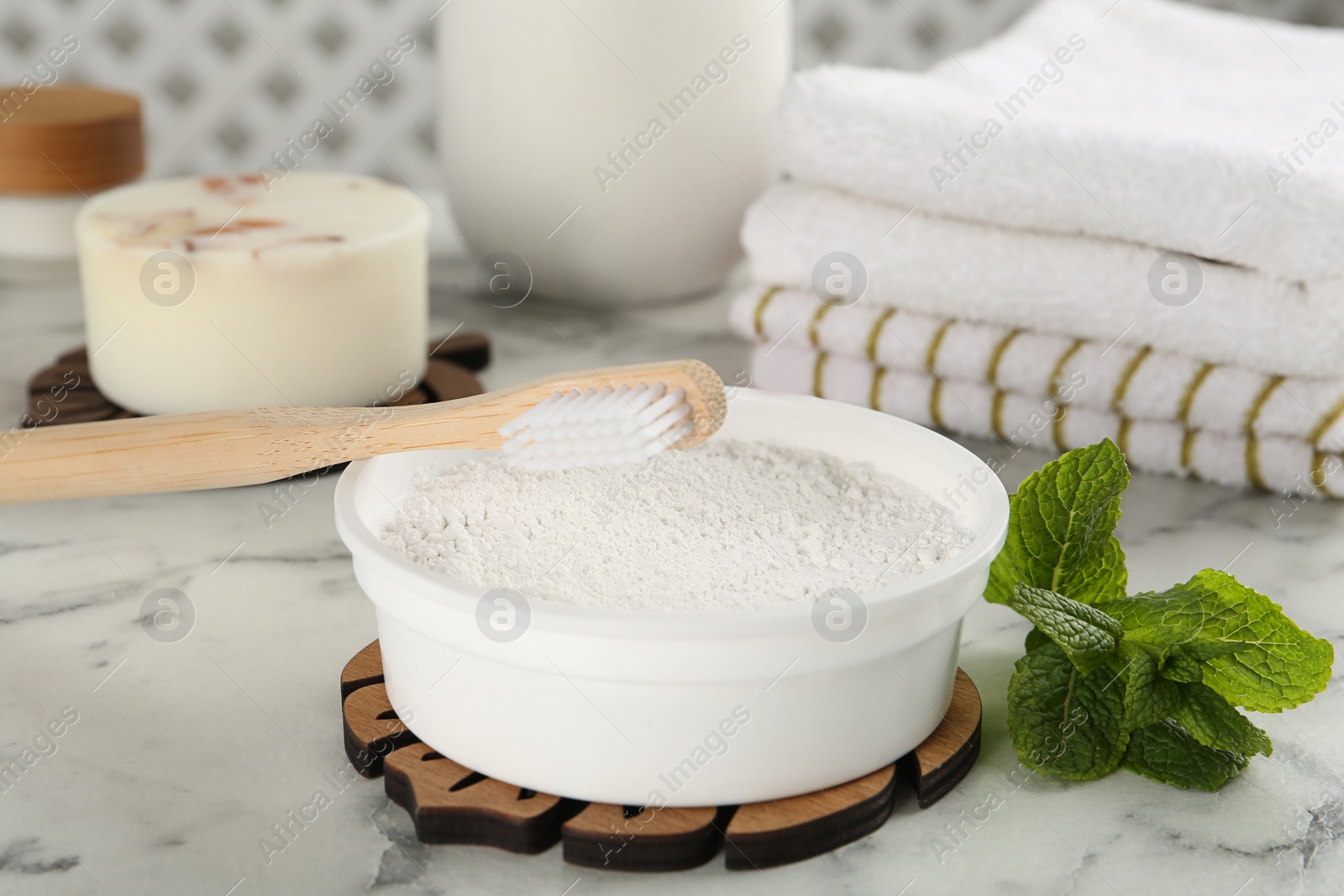 Photo of Tooth powder, brush and mint on white marble table, closeup