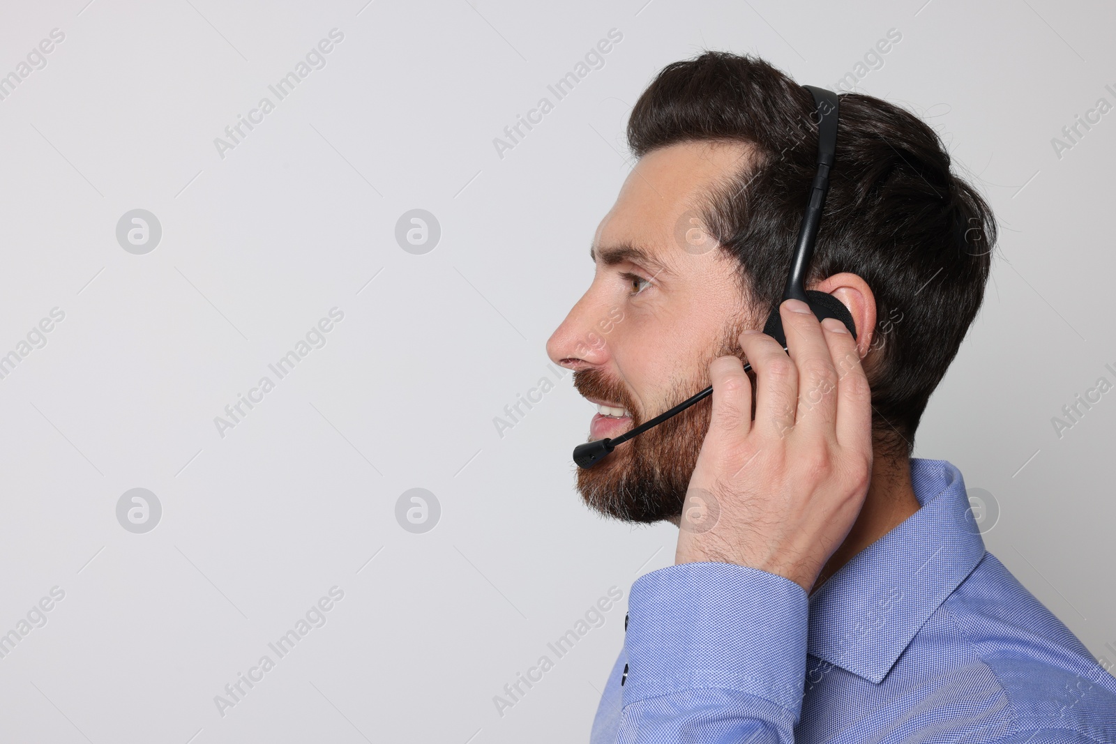 Photo of Hotline operator with headset on light grey background, space for text