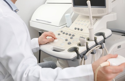Photo of Sonographer operating modern ultrasound machine in clinic, closeup