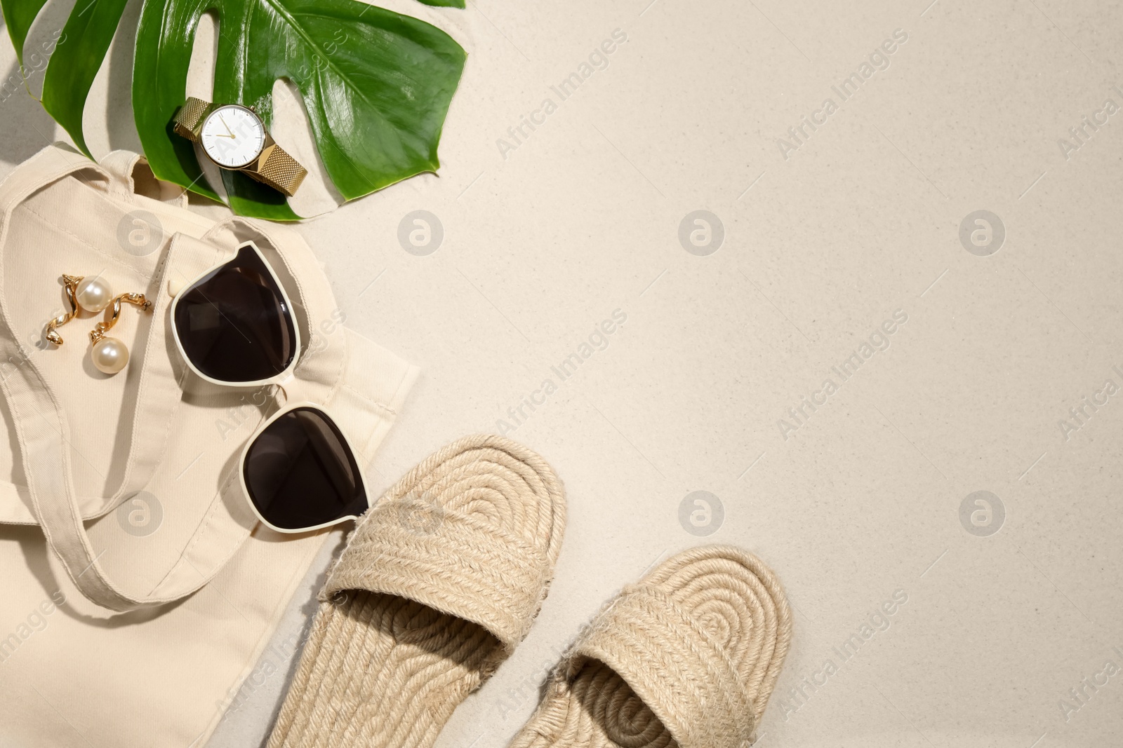 Photo of Flat lay composition with stylish sunglasses and other fashionable accessories on sand. Space for text