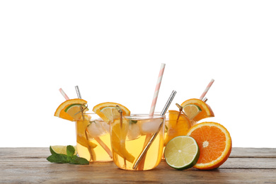 Delicious refreshing drink with orange and lime slices on wooden table against white background