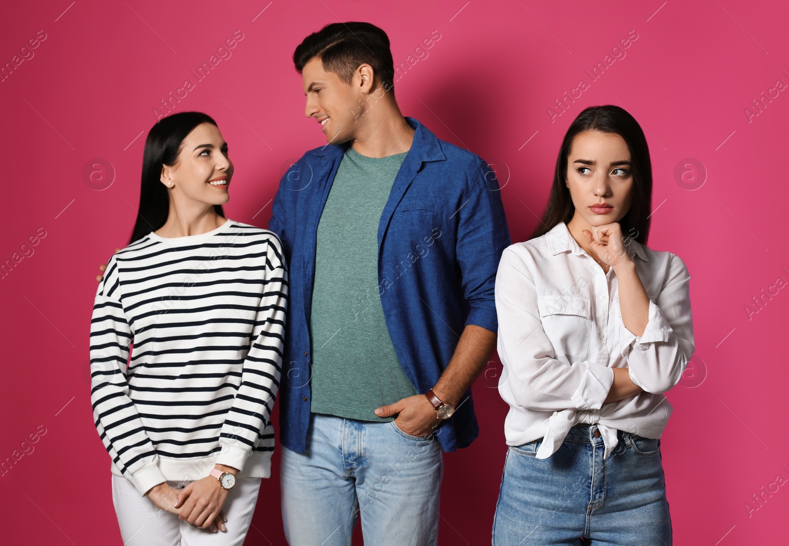 Photo of Unhappy woman feeling jealous while couple spending time together on pink background