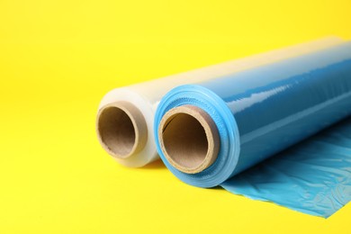 Photo of Rolls of different stretch wrap on yellow background, closeup