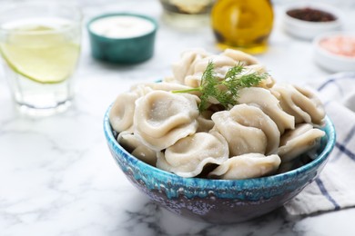 Photo of Tasty dumplings in bowl served on white marble table