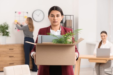 Unemployment problem. Woman with box of personal belongings in office