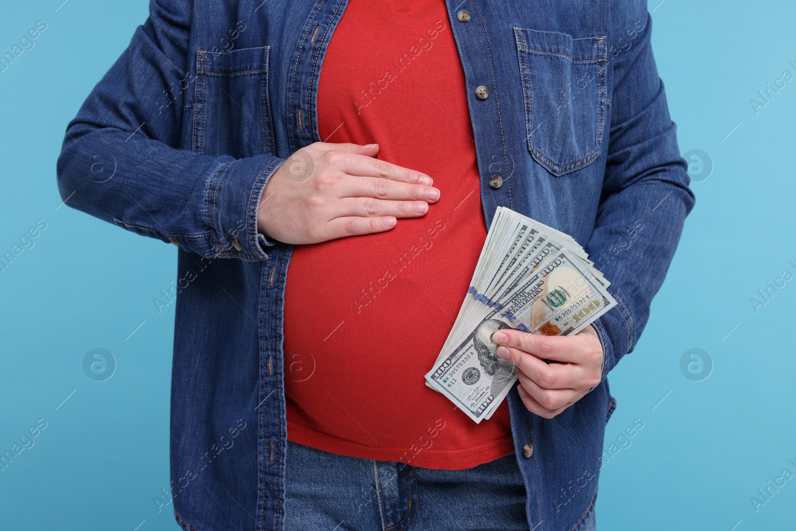 Photo of Surrogate mother. Pregnant woman with dollar banknotes on light blue background, closeup