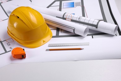 Construction drawings, safety hat, tape measure, pencil and ruler on white background